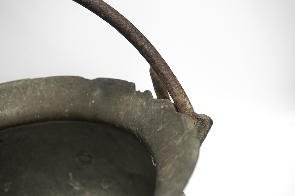 A 16th / 17th century bronze cauldron, 21.5cm tall with handle down. Condition - poor, losses and repairs to rim and body